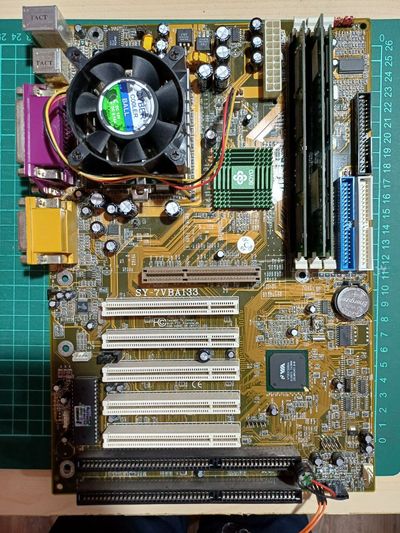 Yellow motherboard with 5 PCI Slots, 1 AGP slot and 2 ISA slots. It has a black cooler, a SOYO green heatsink. Three am slots are populated. The model is SY-7VBA133